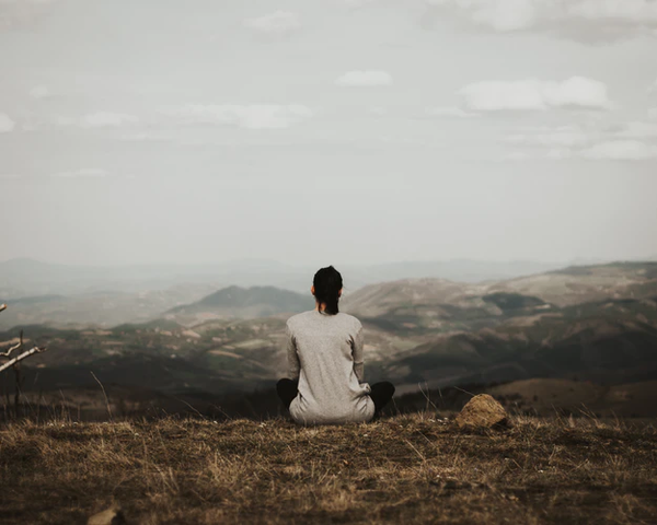 A woman on a mountain meditating to show mindfulness.