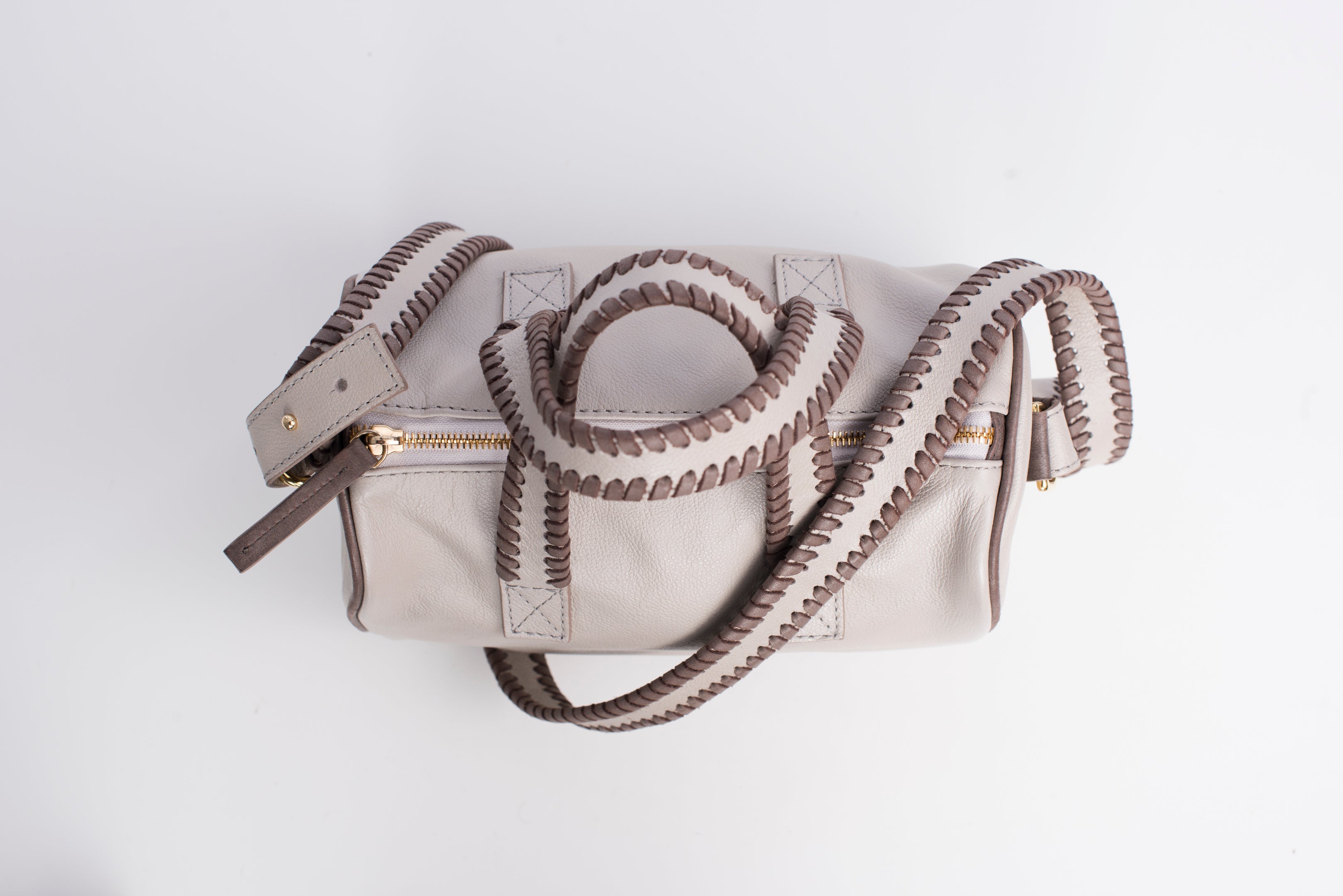 Top view of light colored true north satchel. Detachable straps and handles have whipstitching