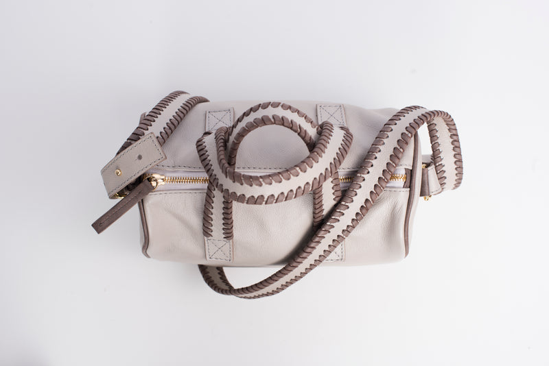 Top view of light colored true north satchel. Detachable straps and handles have whipstitching 